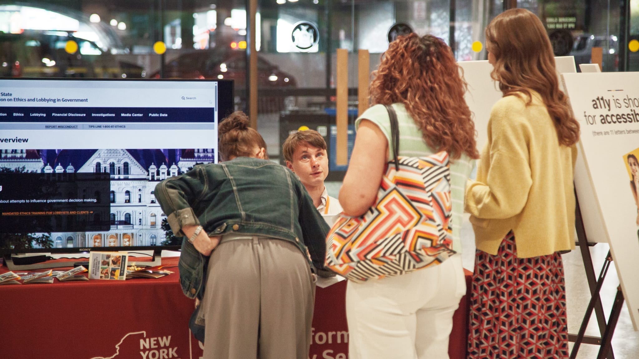 A11y team member Ethan Ligon demonstrates at a table how a screen reader works for a group of passersby.
